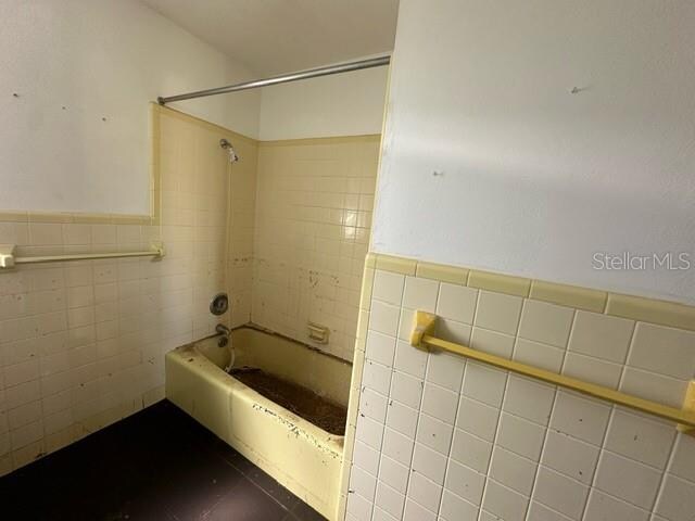 bathroom featuring tile walls and tiled shower / bath