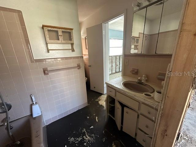 bathroom with vanity, tile walls, and a washtub