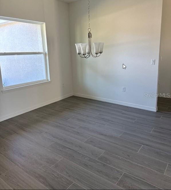 spare room featuring dark hardwood / wood-style flooring and a notable chandelier