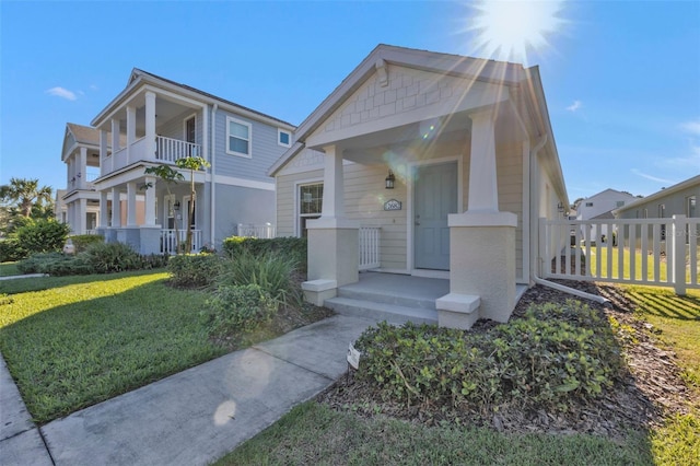 view of front of house featuring a porch, a balcony, and a front lawn