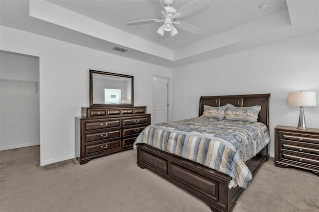 bedroom with light carpet, a closet, a raised ceiling, and ceiling fan