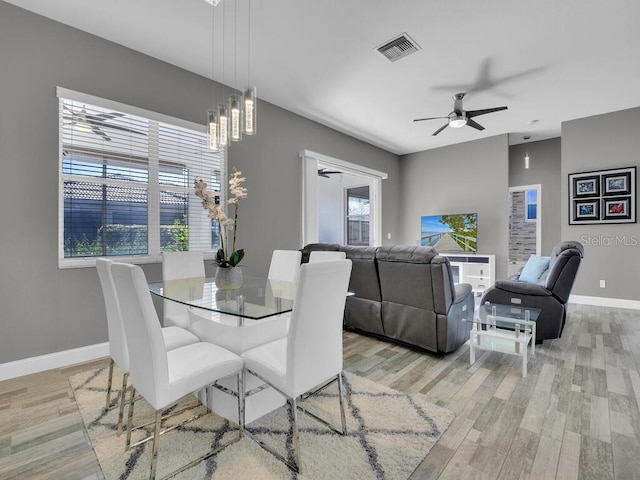 dining space with ceiling fan with notable chandelier and light wood-type flooring