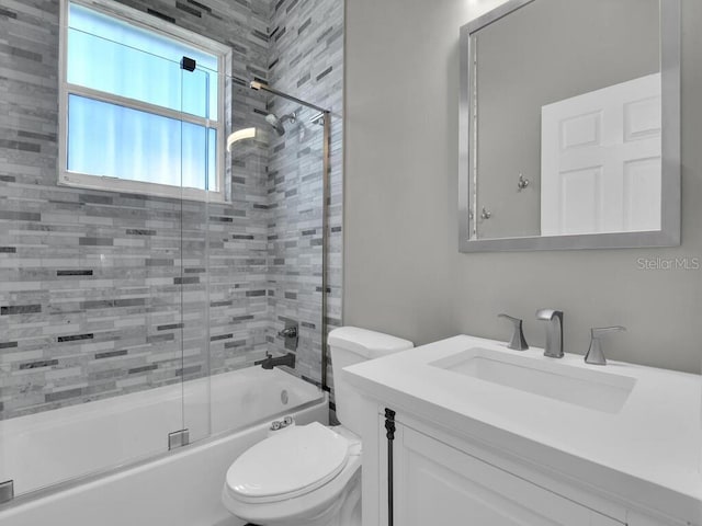 full bathroom featuring vanity, bath / shower combo with glass door, and toilet