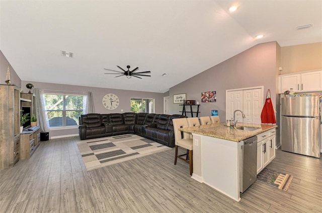 kitchen with white cabinets, appliances with stainless steel finishes, light stone counters, and sink