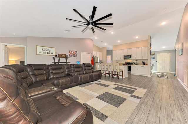 living room with light hardwood / wood-style flooring, vaulted ceiling, and ceiling fan