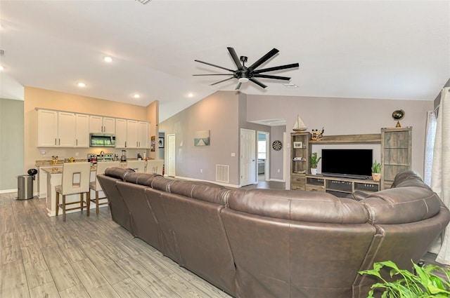 living room with ceiling fan, lofted ceiling, and light hardwood / wood-style flooring