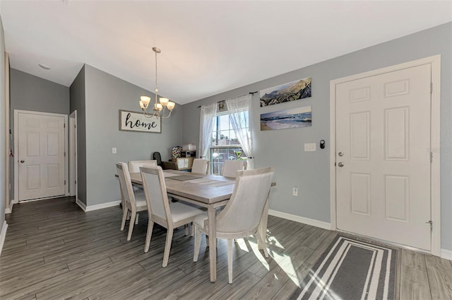 dining space with a notable chandelier, dark wood-type flooring, and vaulted ceiling