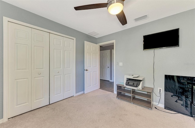 carpeted bedroom with ceiling fan and a closet