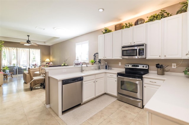 kitchen with white cabinets, stainless steel appliances, kitchen peninsula, and a healthy amount of sunlight