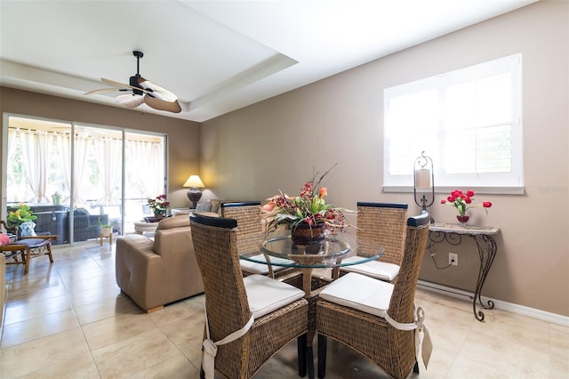 dining room featuring a tray ceiling, ceiling fan, and light tile patterned floors