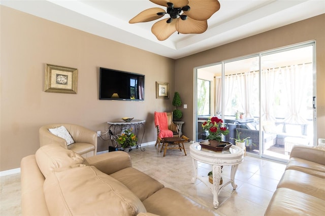 living room with a tray ceiling and ceiling fan