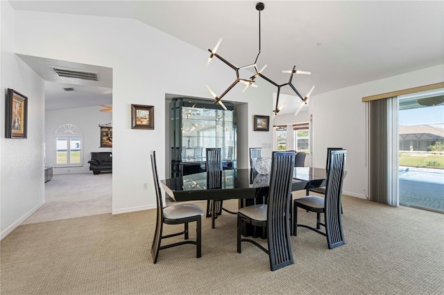 carpeted dining area featuring a chandelier, a healthy amount of sunlight, and vaulted ceiling