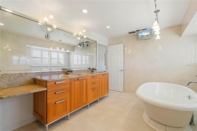 bathroom with a washtub, vanity, tile patterned flooring, and tile walls