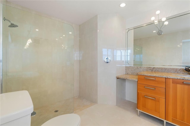 bathroom featuring a tile shower, tile patterned flooring, vanity, and toilet