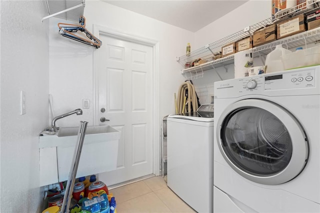 washroom featuring light tile patterned floors, sink, and washing machine and clothes dryer