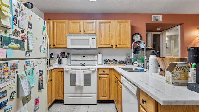 kitchen featuring light stone counters, white appliances, backsplash, and light tile patterned floors