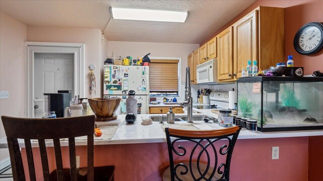 26485 Rampart Blvd Unit E7, Punta Gorda, FL 33983 - kitchen featuring white appliances, a breakfast bar area, light countertops, a peninsula, and a sink