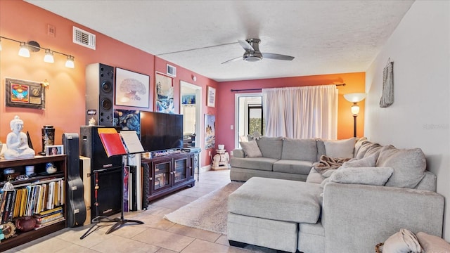 living room featuring ceiling fan, light tile patterned floors, and a textured ceiling