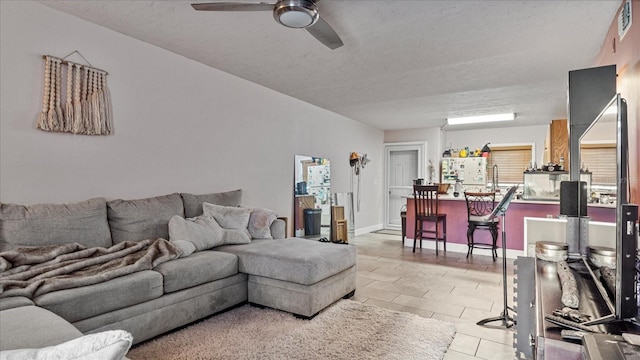 living room with ceiling fan, light tile patterned flooring, and a textured ceiling