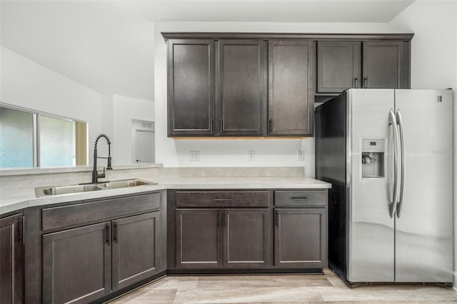 kitchen featuring stainless steel fridge, sink, dark brown cabinets, and light wood-type flooring