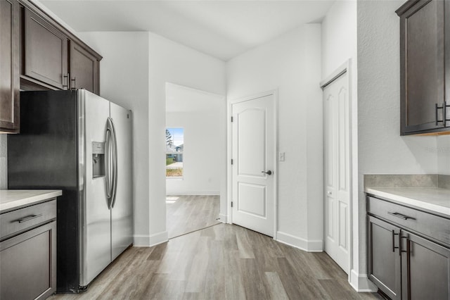 kitchen with stainless steel fridge, dark brown cabinetry, and light hardwood / wood-style floors