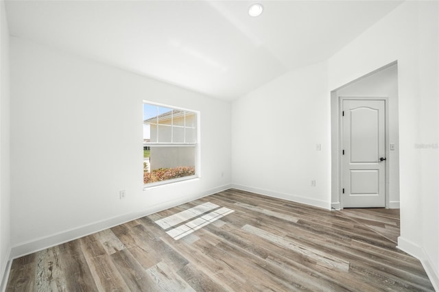 empty room featuring hardwood / wood-style floors and vaulted ceiling