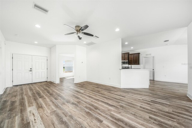 unfurnished living room featuring ceiling fan and dark hardwood / wood-style flooring