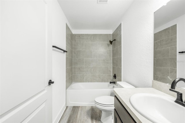 full bathroom featuring hardwood / wood-style flooring, vanity, toilet, and tiled shower / bath