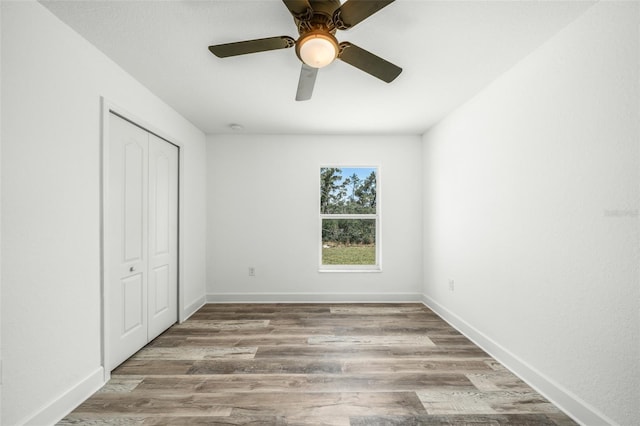 unfurnished bedroom with ceiling fan, wood-type flooring, and a closet