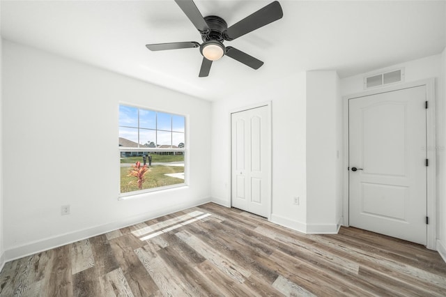 unfurnished bedroom with a closet, hardwood / wood-style flooring, and ceiling fan