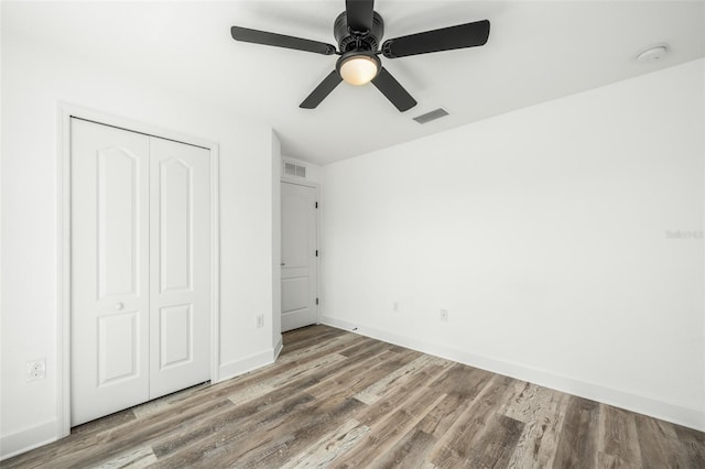 unfurnished bedroom featuring hardwood / wood-style floors, a closet, and ceiling fan