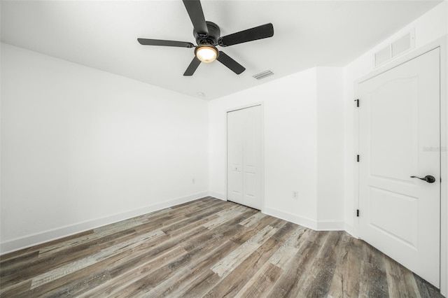 unfurnished bedroom with ceiling fan, wood-type flooring, and a closet