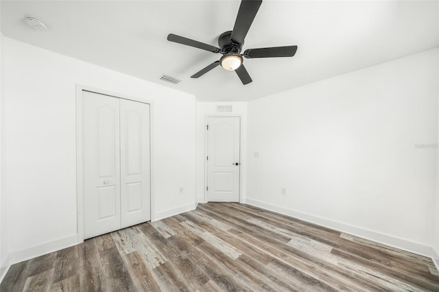 unfurnished bedroom featuring ceiling fan, a closet, and hardwood / wood-style flooring