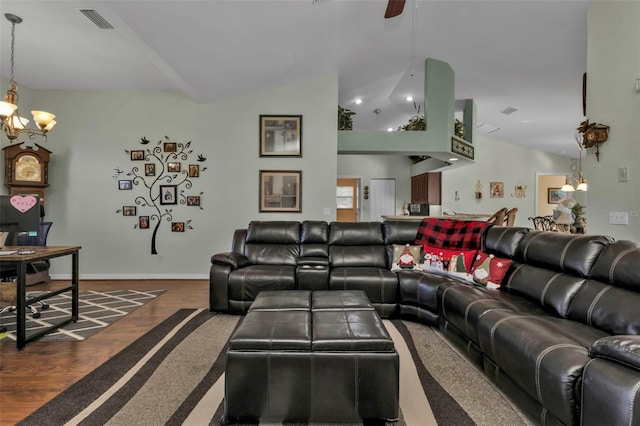 living room with ceiling fan with notable chandelier, dark wood-type flooring, and lofted ceiling