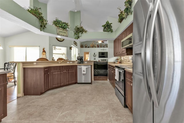 kitchen featuring high vaulted ceiling, decorative backsplash, dark brown cabinets, light tile patterned floors, and appliances with stainless steel finishes