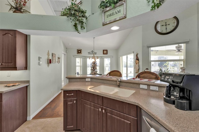 kitchen with dark brown cabinetry, sink, decorative light fixtures, vaulted ceiling, and light wood-type flooring