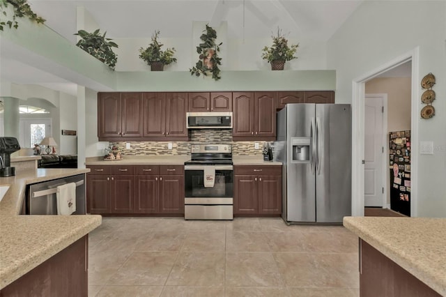 kitchen featuring appliances with stainless steel finishes, light tile patterned floors, high vaulted ceiling, and dark brown cabinetry