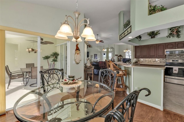 dining room featuring ceiling fan with notable chandelier and light hardwood / wood-style flooring