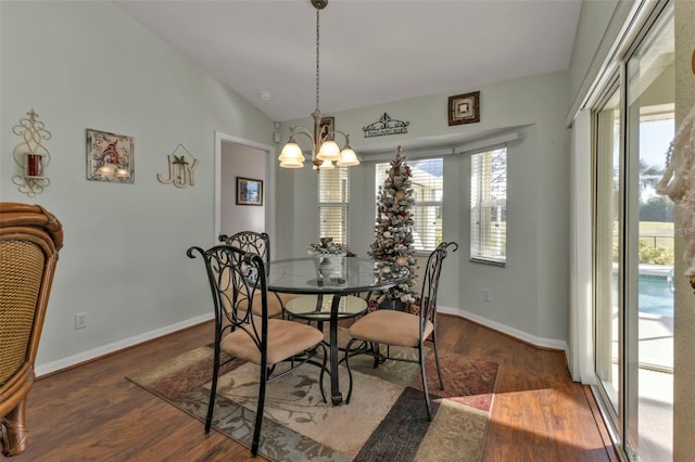 dining space featuring vaulted ceiling, dark hardwood / wood-style floors, and an inviting chandelier