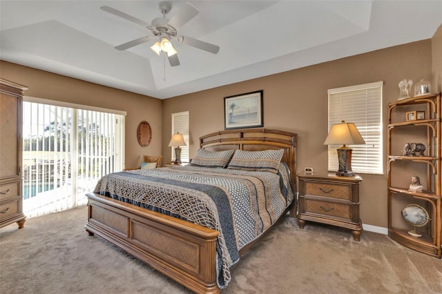 bedroom featuring a tray ceiling, access to exterior, ceiling fan, and carpet floors