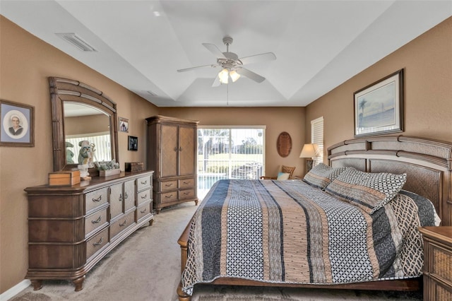 carpeted bedroom featuring a raised ceiling and ceiling fan