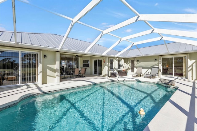 view of swimming pool featuring a patio, glass enclosure, and ceiling fan