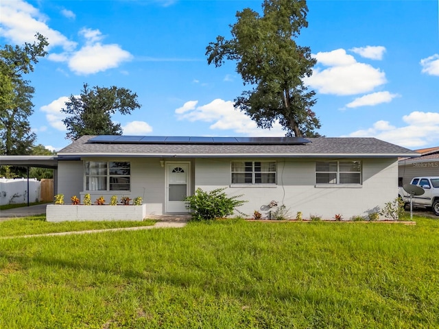 ranch-style home with solar panels and a front lawn