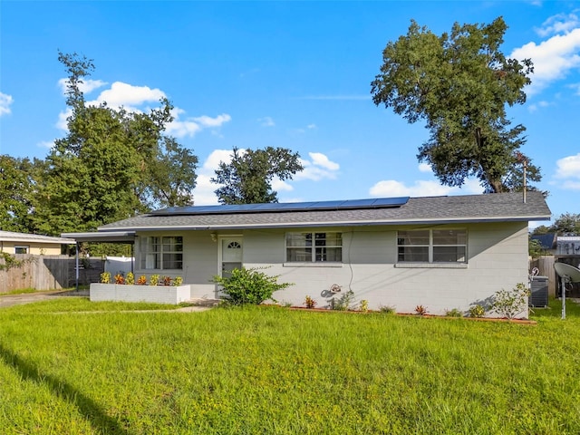 single story home with central AC, a front yard, and solar panels