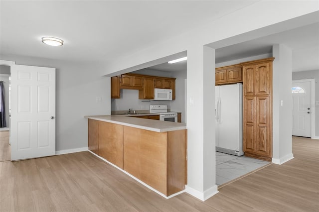 kitchen featuring kitchen peninsula, white appliances, and light hardwood / wood-style floors