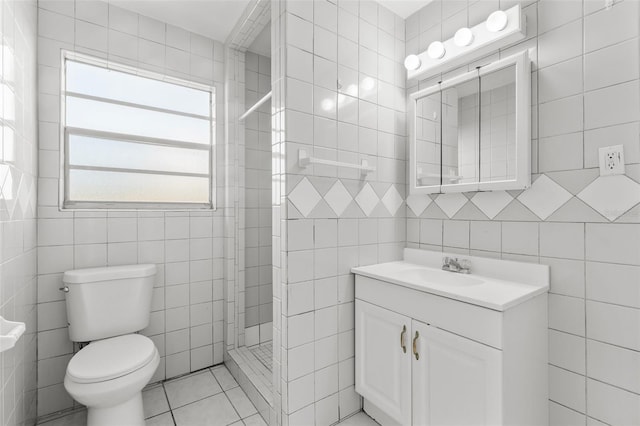 bathroom with vanity, tile patterned floors, toilet, tile walls, and walk in shower