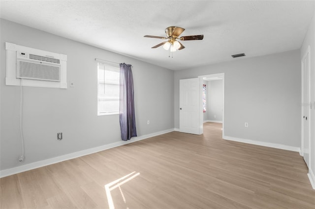 empty room featuring ceiling fan, an AC wall unit, a textured ceiling, and light hardwood / wood-style flooring