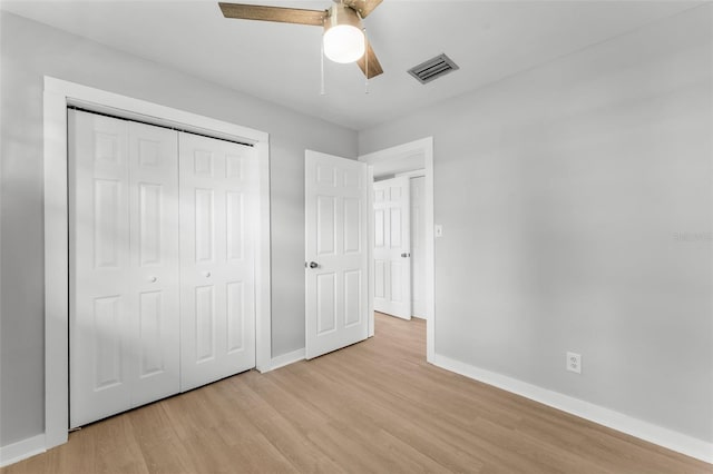 unfurnished bedroom with ceiling fan, light wood-type flooring, and a closet