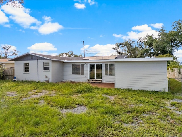 rear view of house featuring solar panels and a yard