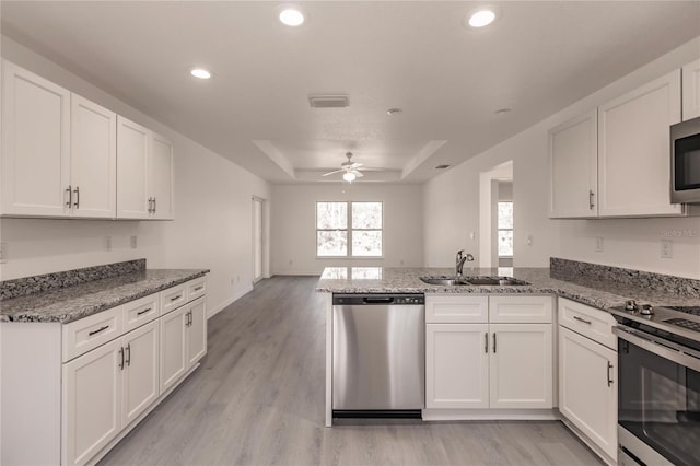 kitchen with kitchen peninsula, appliances with stainless steel finishes, and white cabinetry